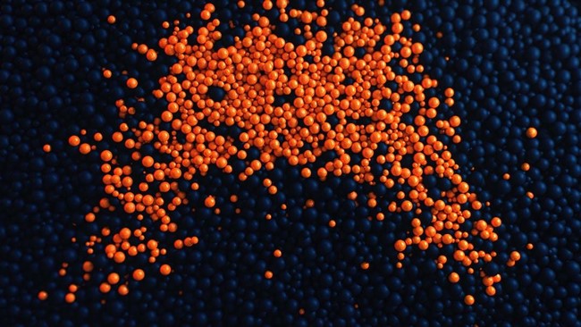 A group of orange beads scattered across a black background representing the scattered nature of a scatter chart.