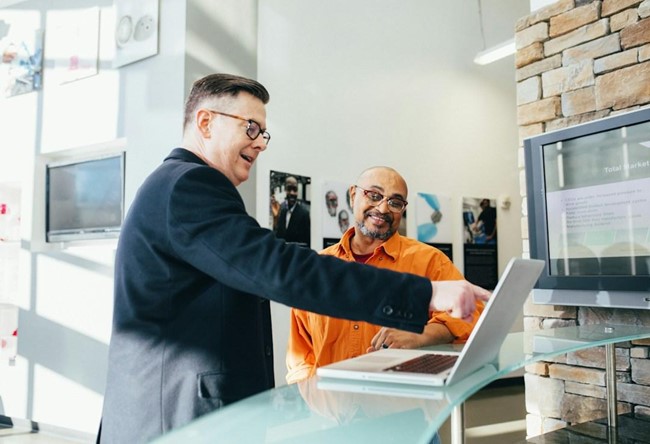 A sales coach and a sales representative at a table, with the coach providing personalized feedback on the representative's sales pitch.